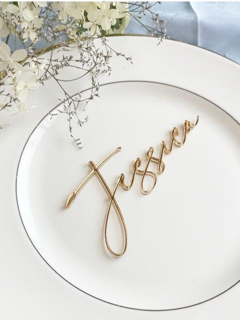 May include: A white plate with a gold rim and a gold cursive name card that says 'Jessica'.