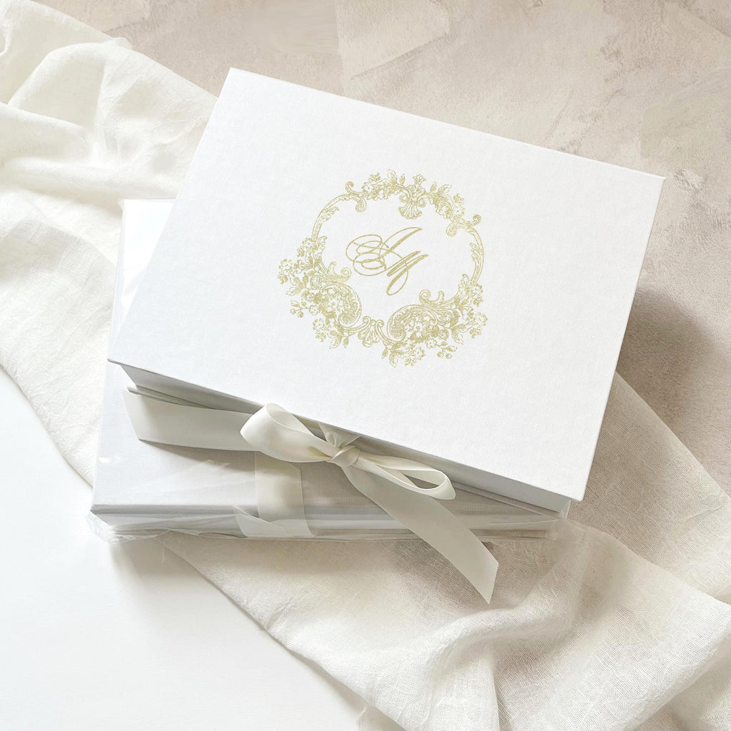 White linen wedding invitation box with gold foil monogram with insert for leather tag and passport.